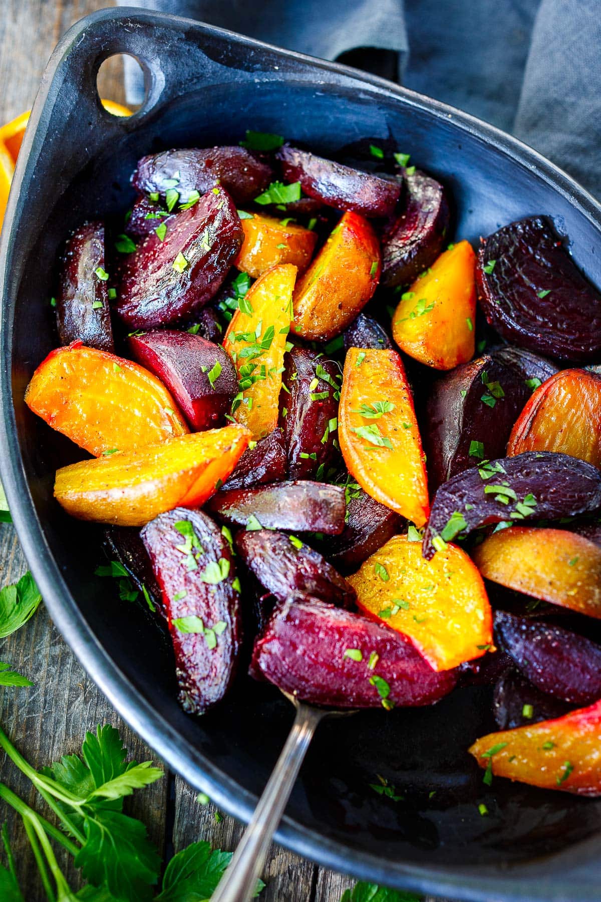 roasted beets with fresh herbs in dish with serving spoon.