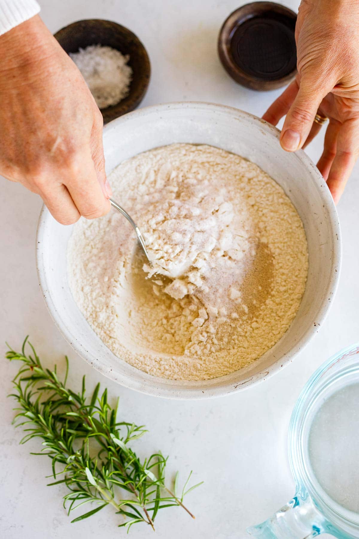 hands using a fork to mix salt and flour in large bowl.